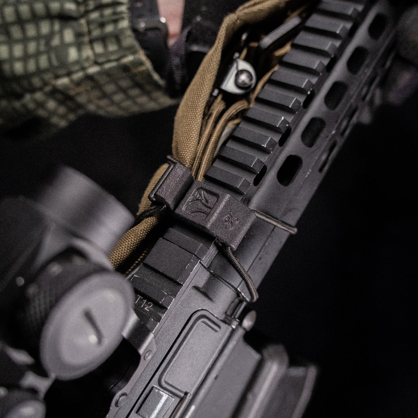 A black bungee cord sling system designed to be mounted on a Picatinny rail for stowing and deploying a sling.