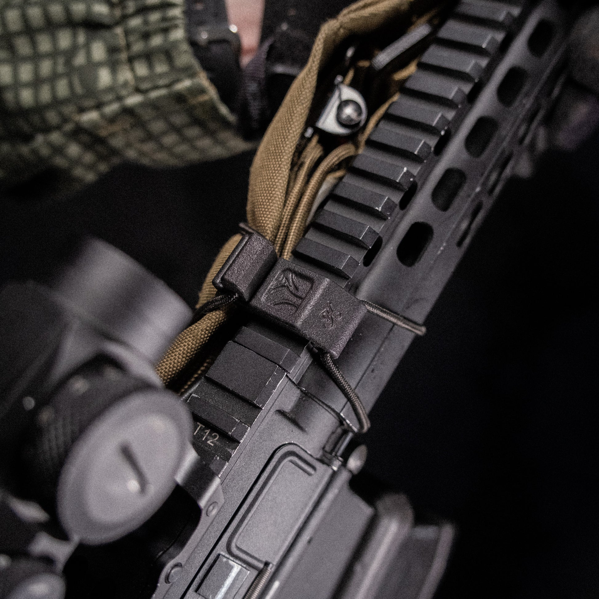 A black bungee cord sling system designed to be mounted on a Picatinny rail for stowing and deploying a sling.